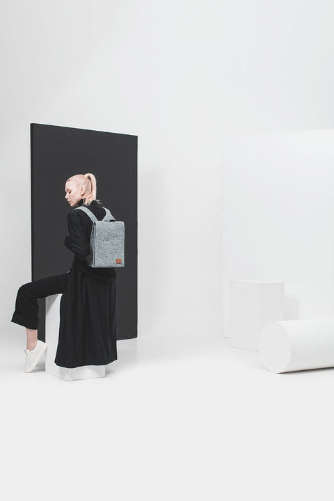 1. Woman wearing Nordhale Lund Mini Backpack in grey, styled in a minimalist studio setting