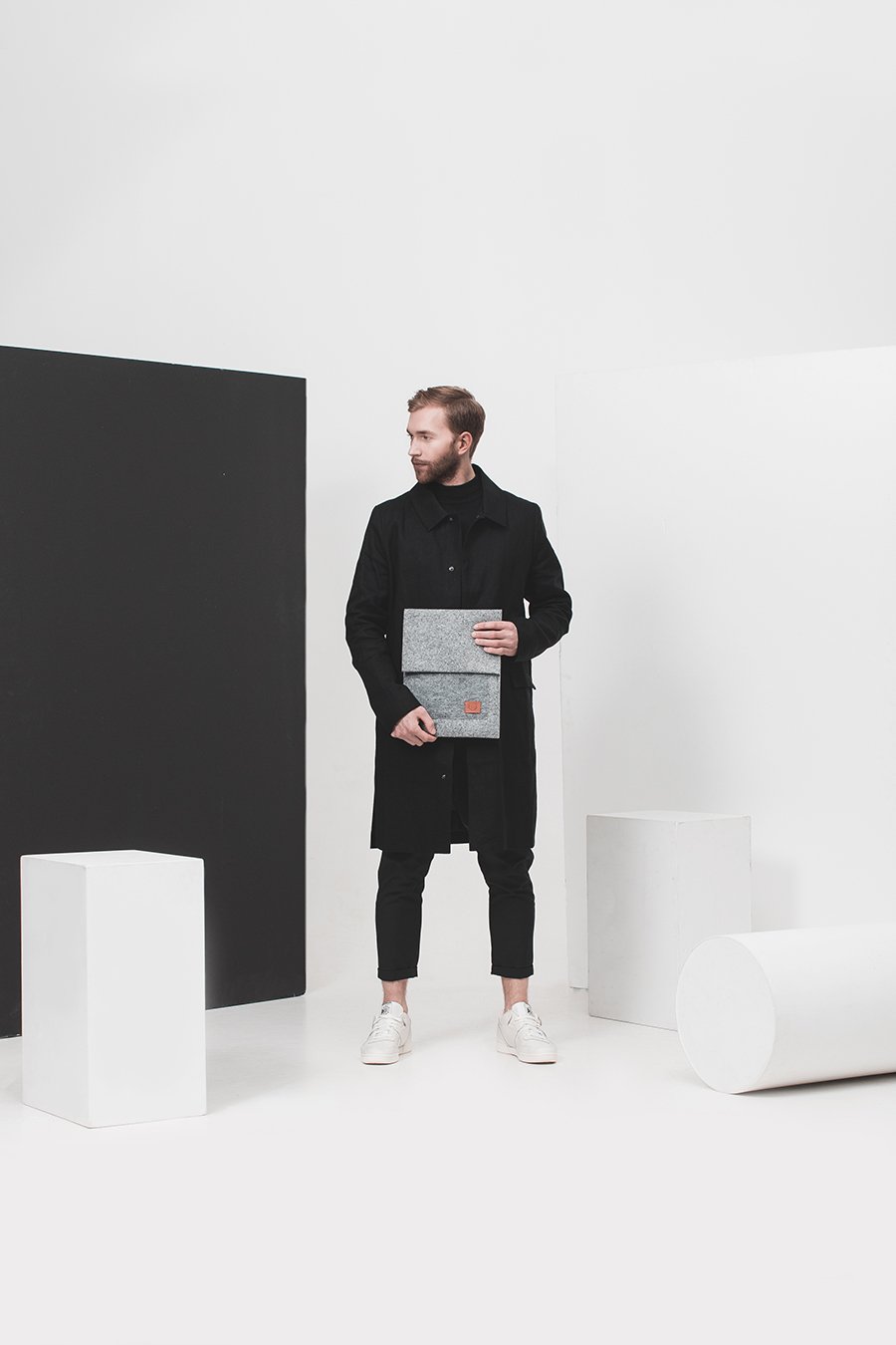 1. Man holding Nordhale Malmö grey laptop sleeve in minimalist studio setting