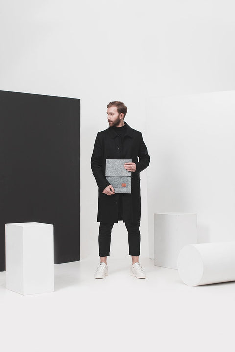 1. Man holding Nordhale Malmö 13' Grey Laptop Sleeve in minimalist studio setting