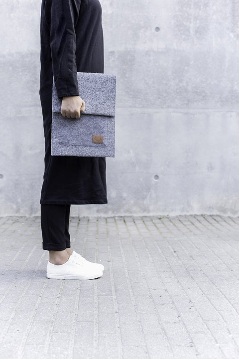2. Woman carrying Nordhale Malmö grey laptop sleeve outdoors, showcasing slim design