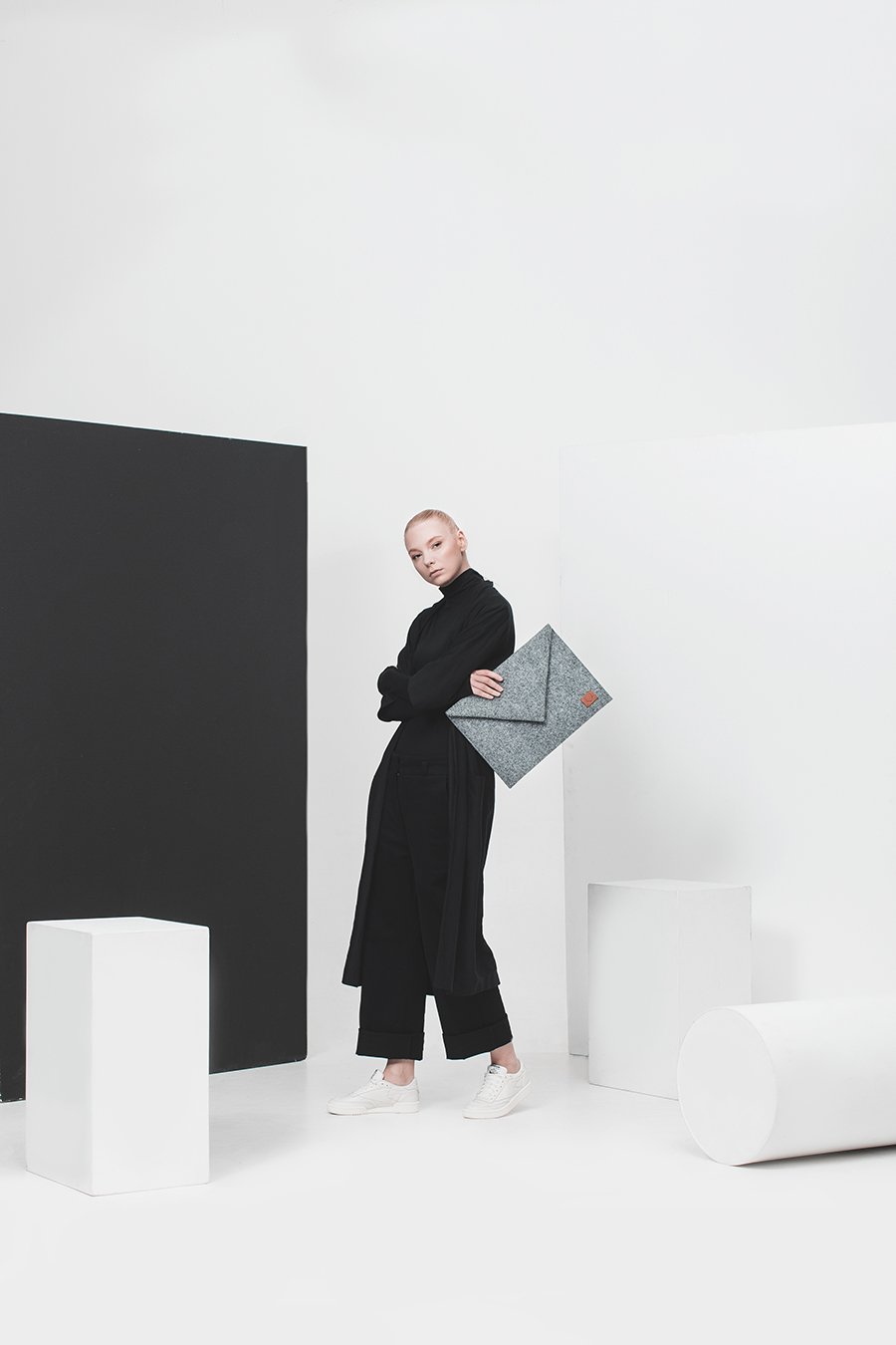 1. Woman holding Nordhale Skive grey clutch laptop case in a minimalist studio setting