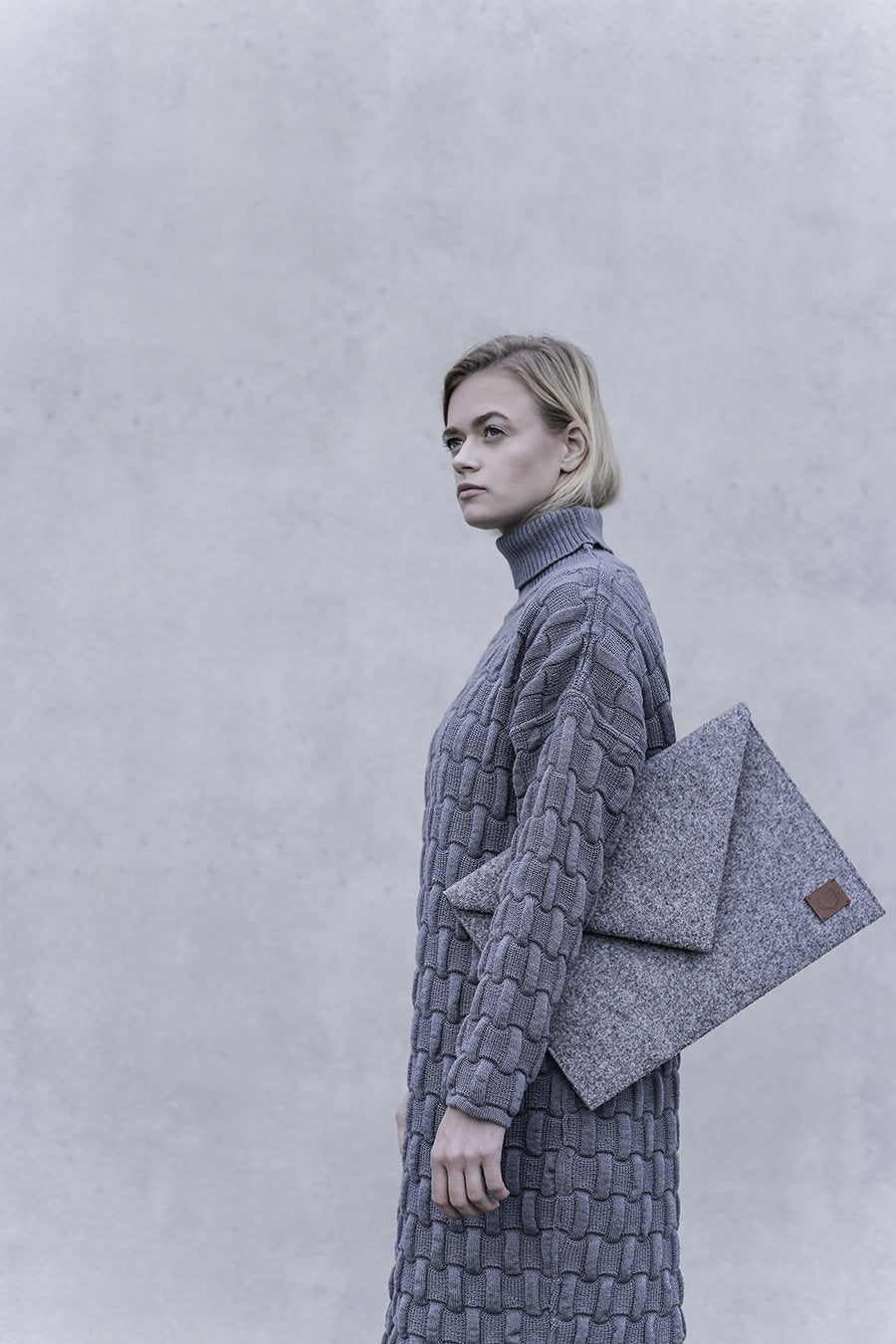 2. Woman carrying Nordhale Skive grey clutch laptop case against a neutral background