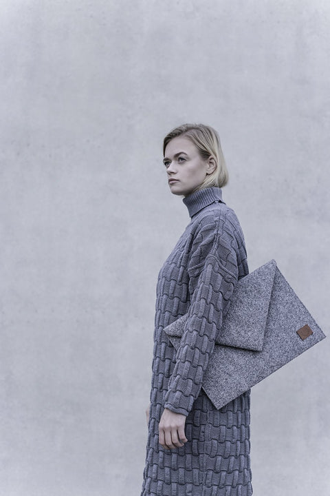 2. Woman carrying Nordhale Skive grey clutch laptop case against a neutral background