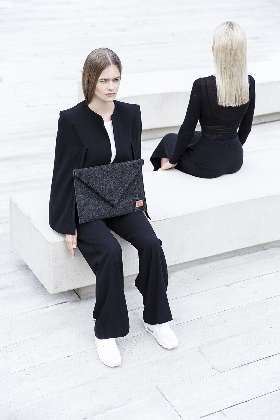 1. Women's Nordhale Skive black clutch and laptop case held by model in outdoor setting