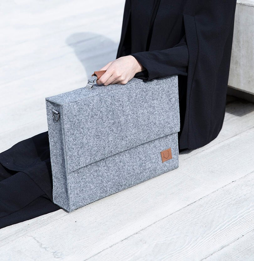 4. Woman seated with Nordhale grey Briefcase Sören, demonstrating minimalistic and functional design