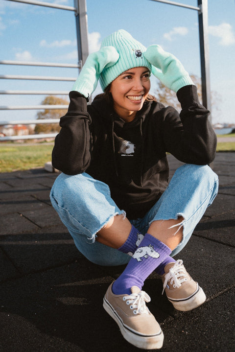 1. Unisex black Moomin hoodie worn by female model sitting outdoors, styled with jeans and colorful accessories