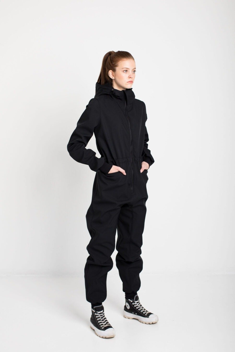 4. Women's KRISTINA softshell overall by Nuckö in black, side view in studio setting with model hands in pockets