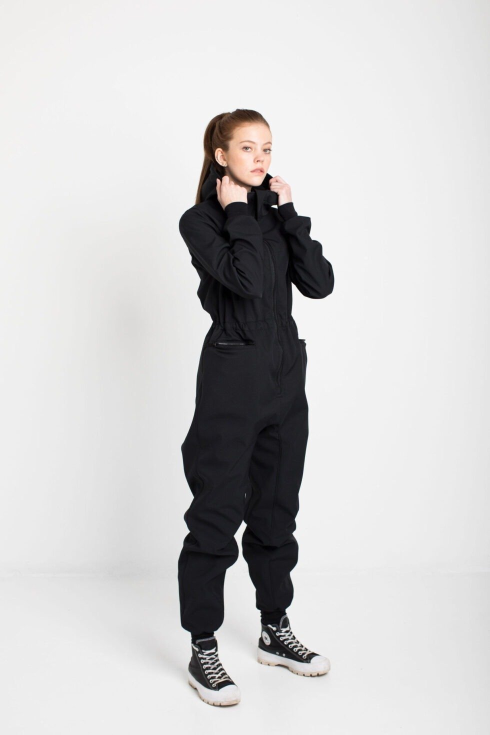 1. Women's KRISTINA softshell overall by Nuckö in black, shown in studio setting with model adjusting collar