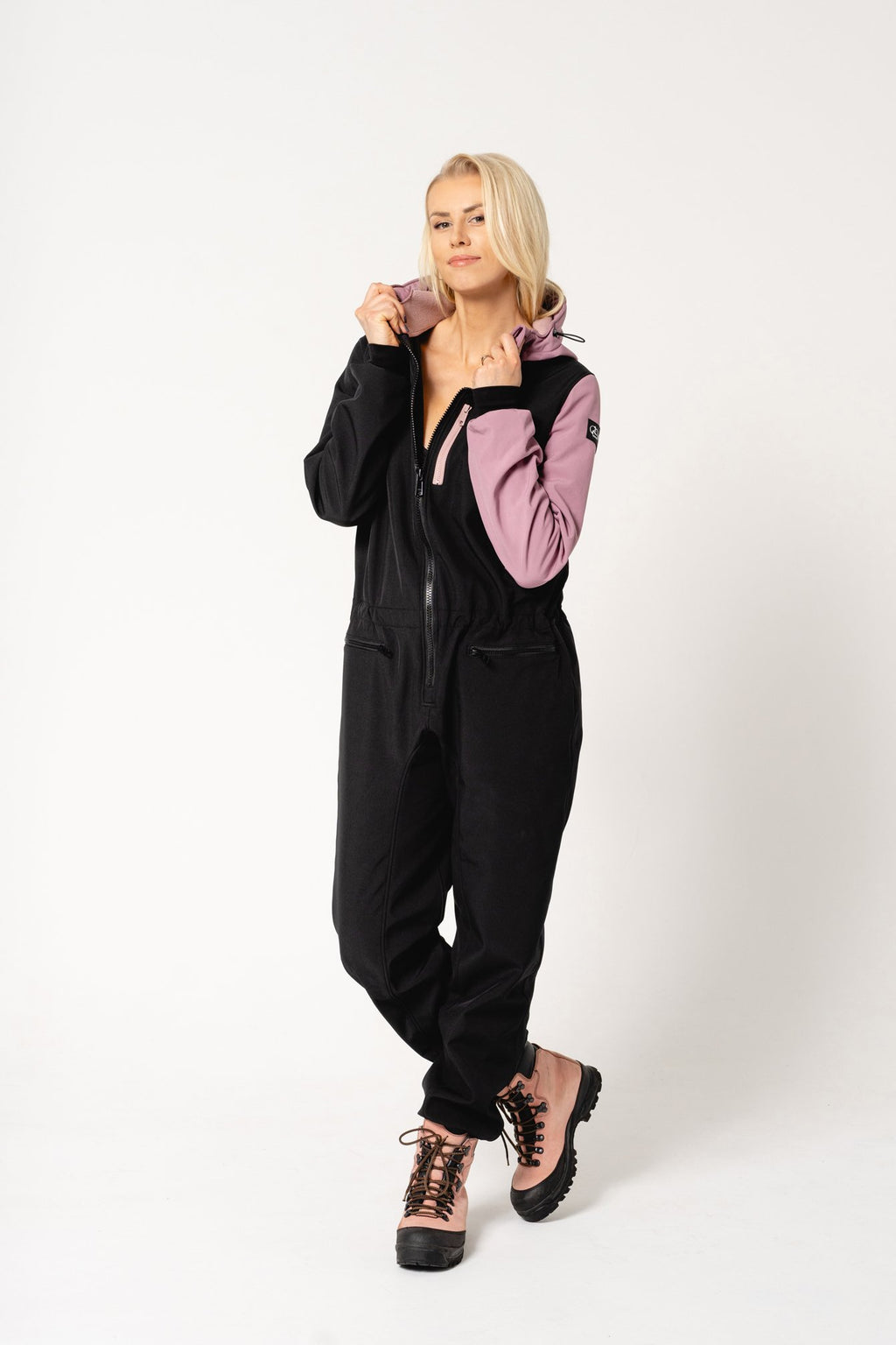 4. Women's Eeva softshell overall by Nuckö in black and pink, model adjusting hood in studio