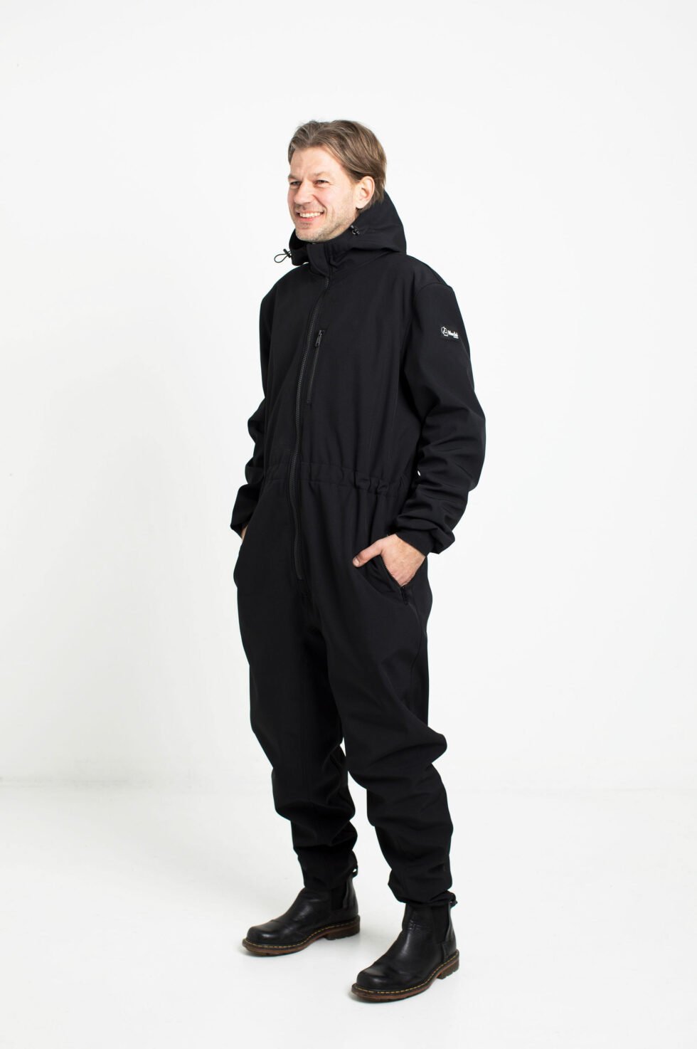 3. Man smiling in black Nuckö RÜNNO softshell overall with hood in studio