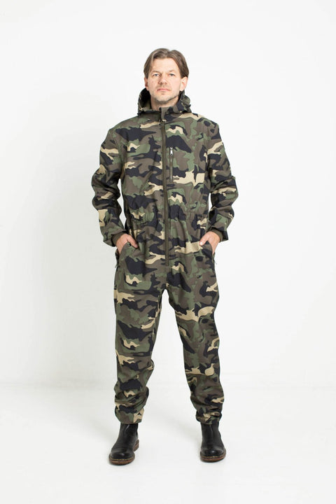 1. Man wearing Nuckö RINGO softshell overall in camouflage pattern standing with hands in pockets in studio setting