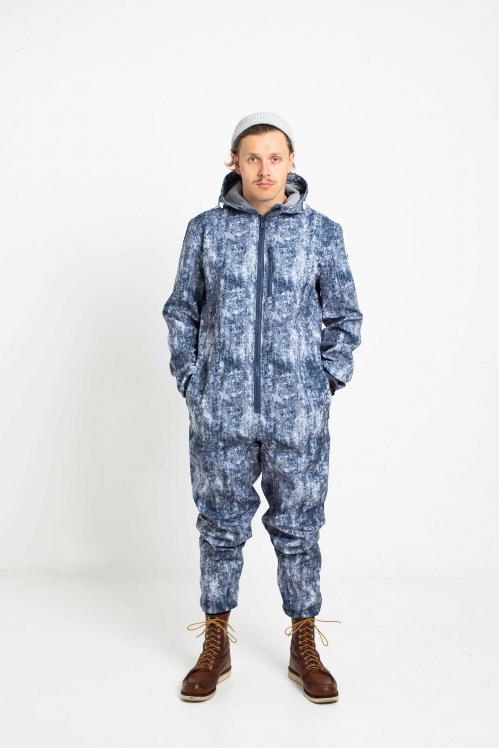 3. Man wearing Nuckö ERGO softshell overall with blue digital print, standing in studio with hands in pockets
