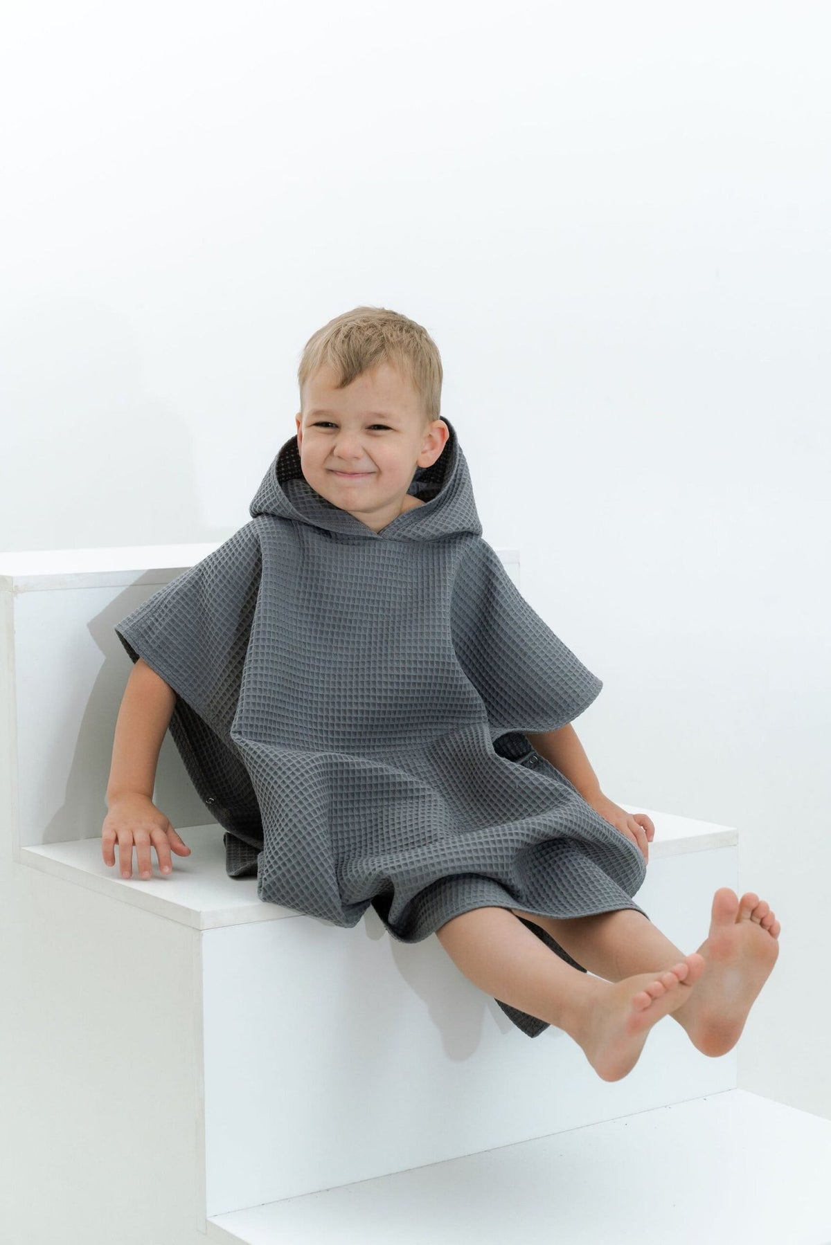 2. Boy in gray waffle fabric poncho with hood sitting on white steps