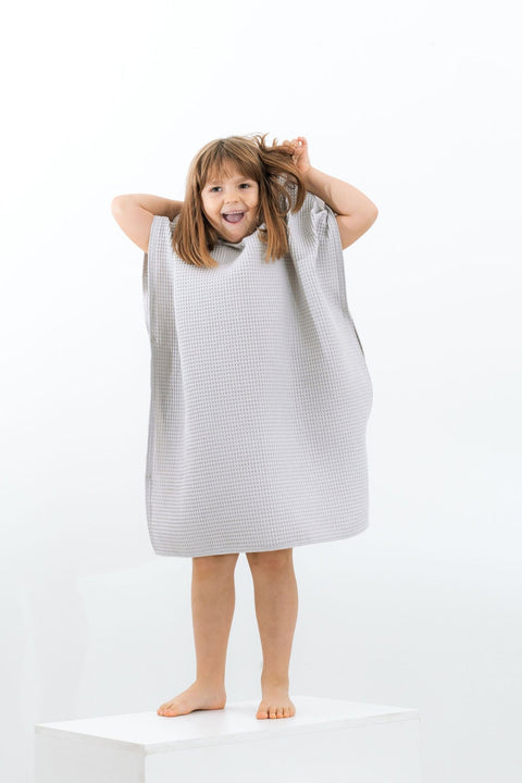 5. Girl in light gray waffle fabric poncho with hood playing with hair