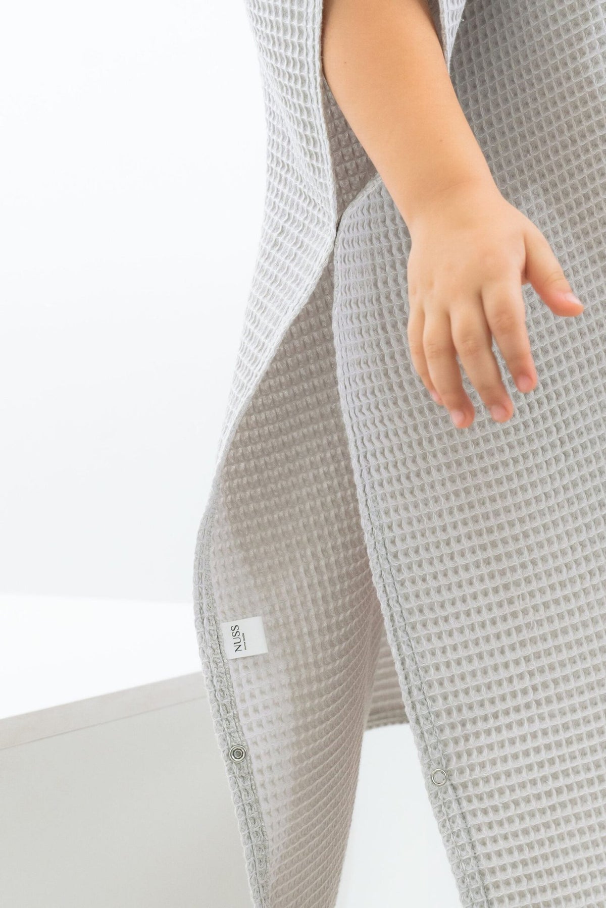 12. Close-up of light gray waffle fabric poncho showing texture and side detail with label