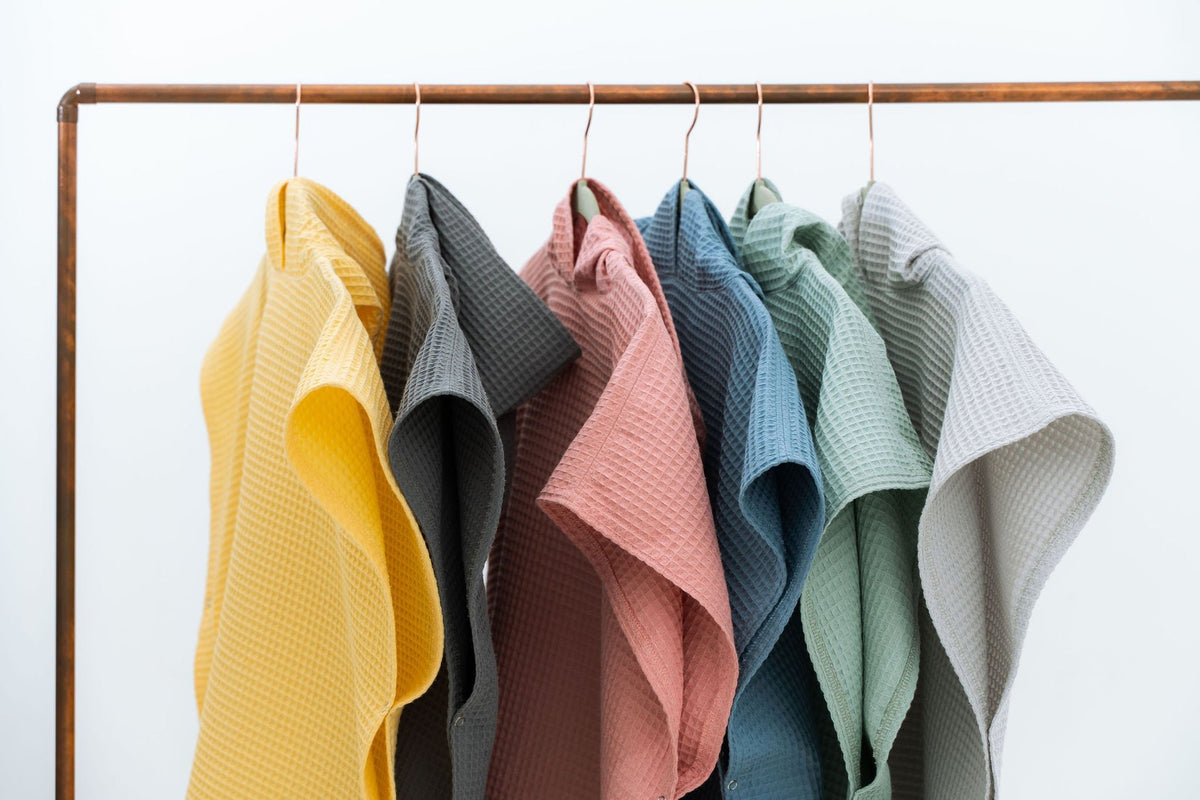 8. Hanging waffle fabric ponchos in various colors on copper rod