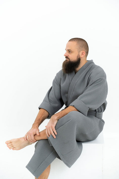2. Man sitting wearing grey waffle robe with folded sleeves on white background