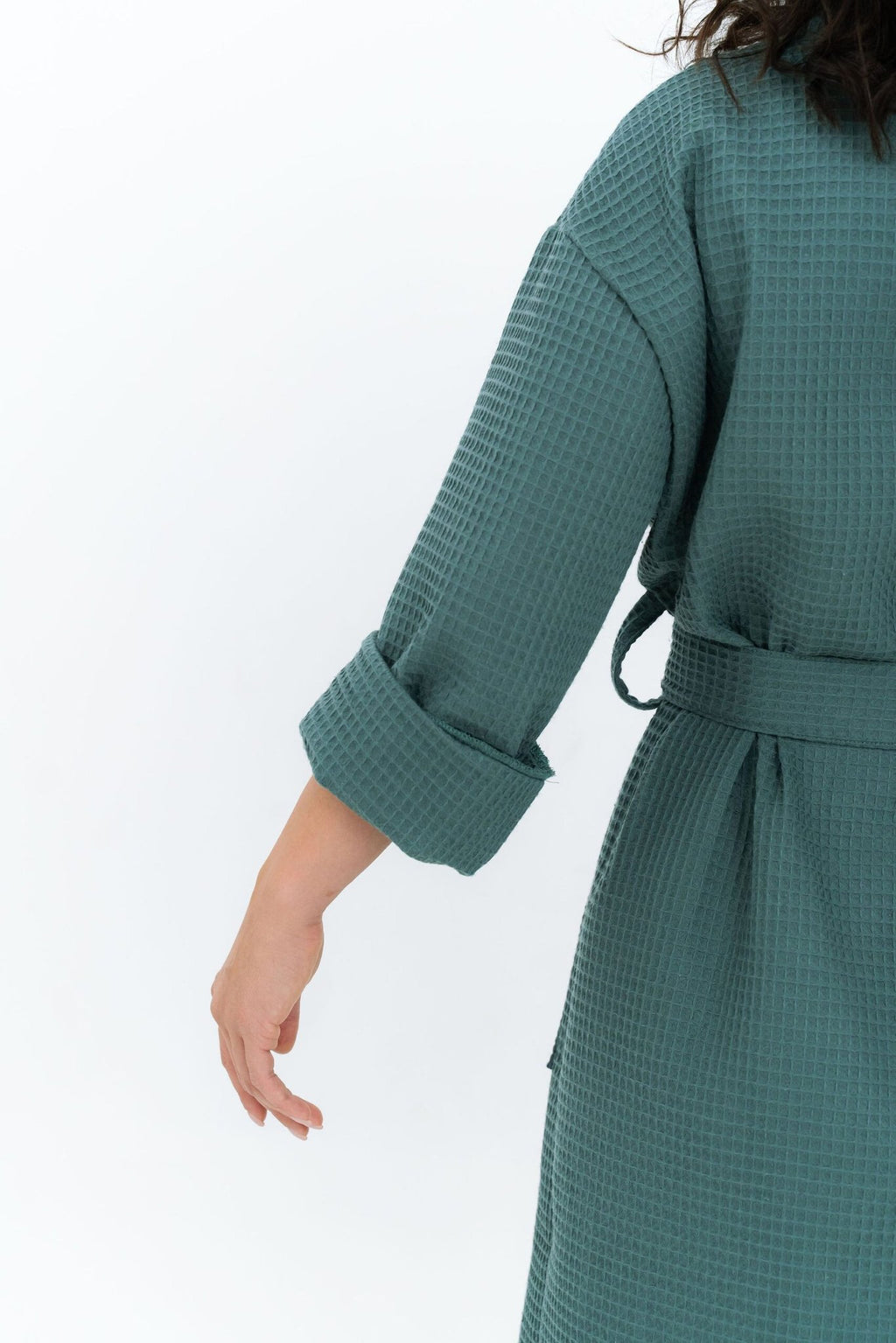 3. Back view of woman in teal waffle fabric robe with rolled-up sleeves, showing texture