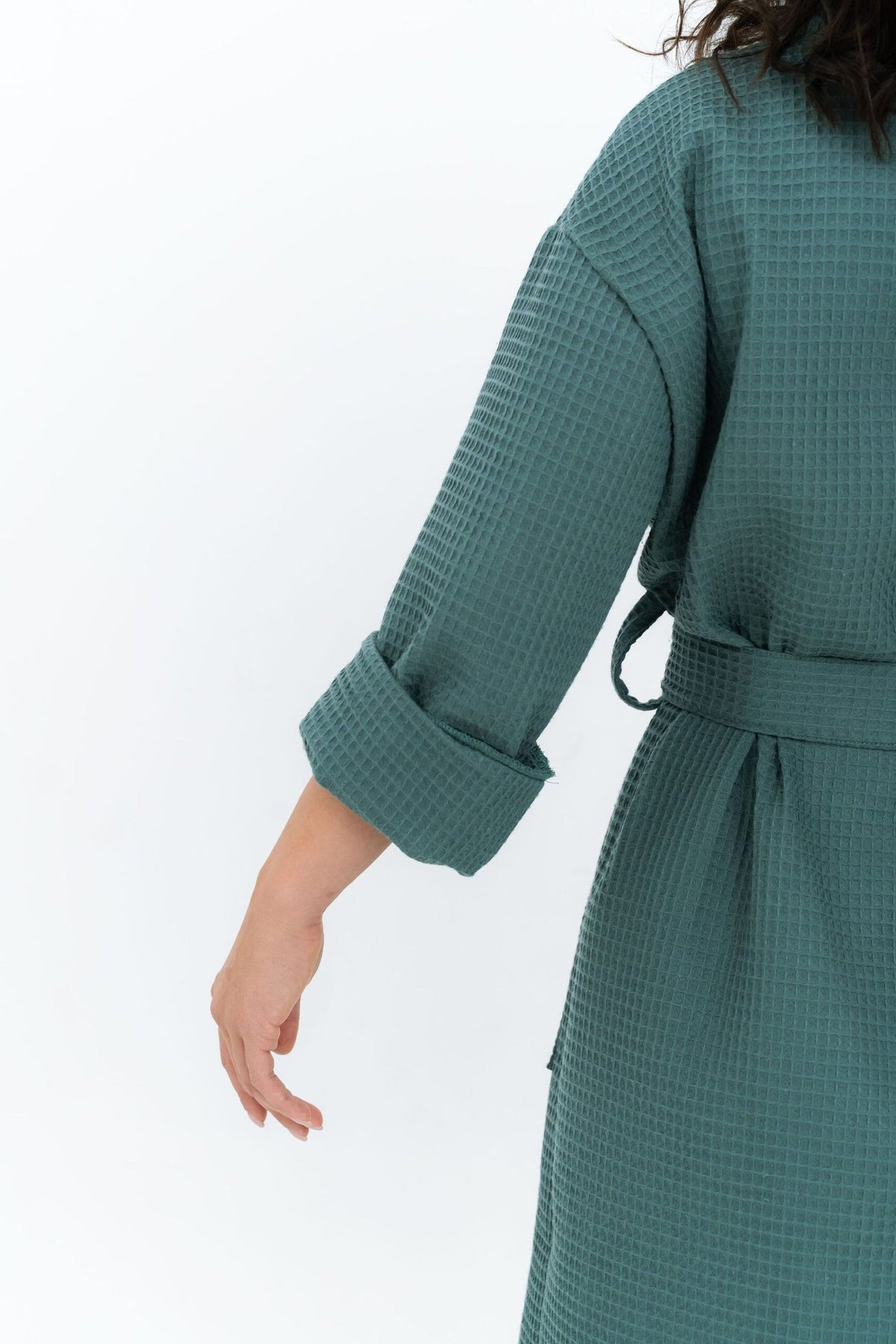 3. Back view of woman in teal waffle fabric robe with rolled-up sleeves, showing texture