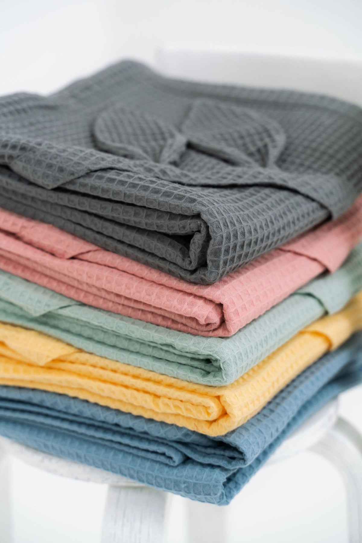 3. Close-up of folded waffle fabric towels in gray, pink, green, yellow, and blue with bunny ears