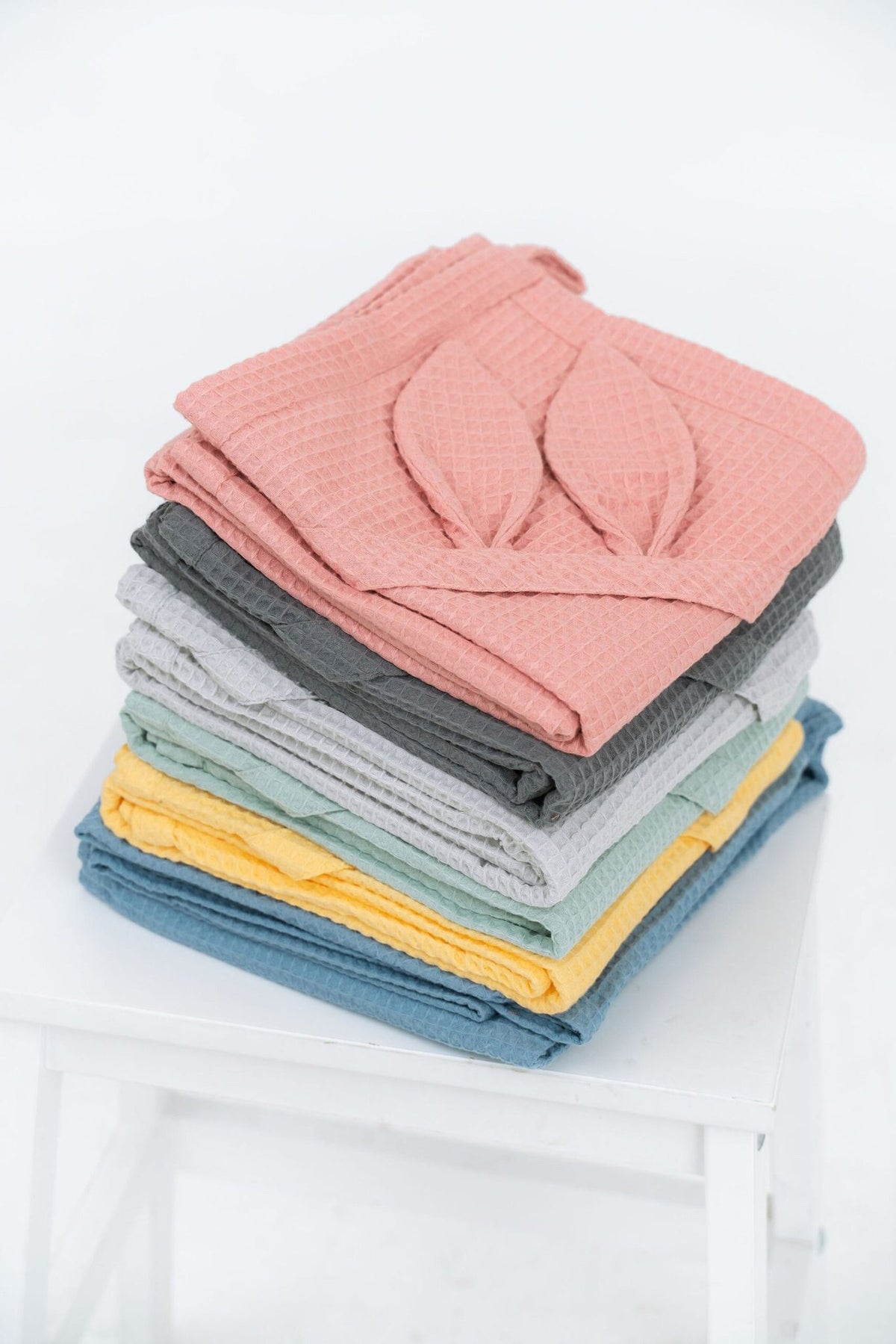 2. Stack of waffle fabric towels in various colors with visible bunny ears on top towel