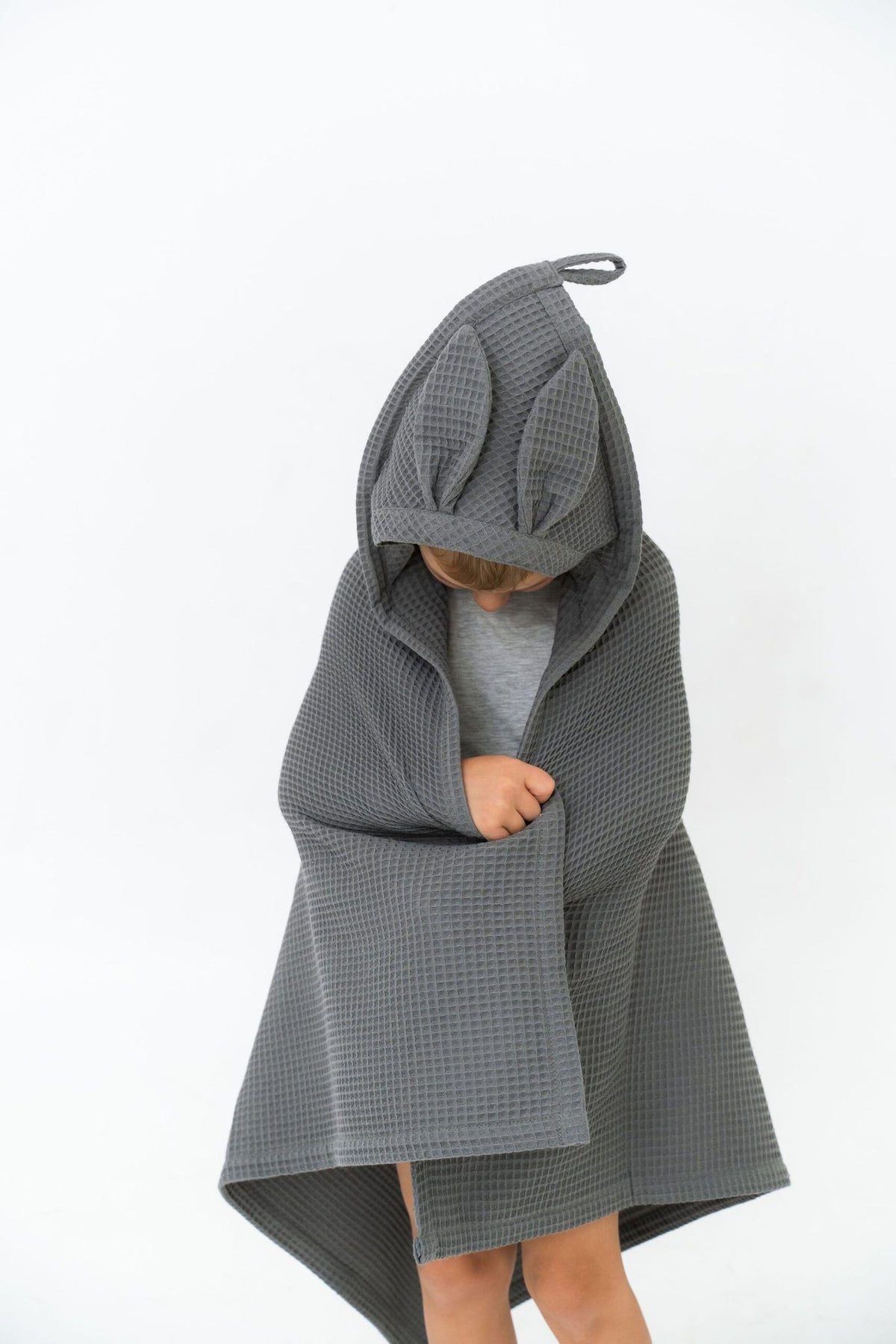 4. Child wrapped in gray waffle fabric towel with bunny ears hood looking down
