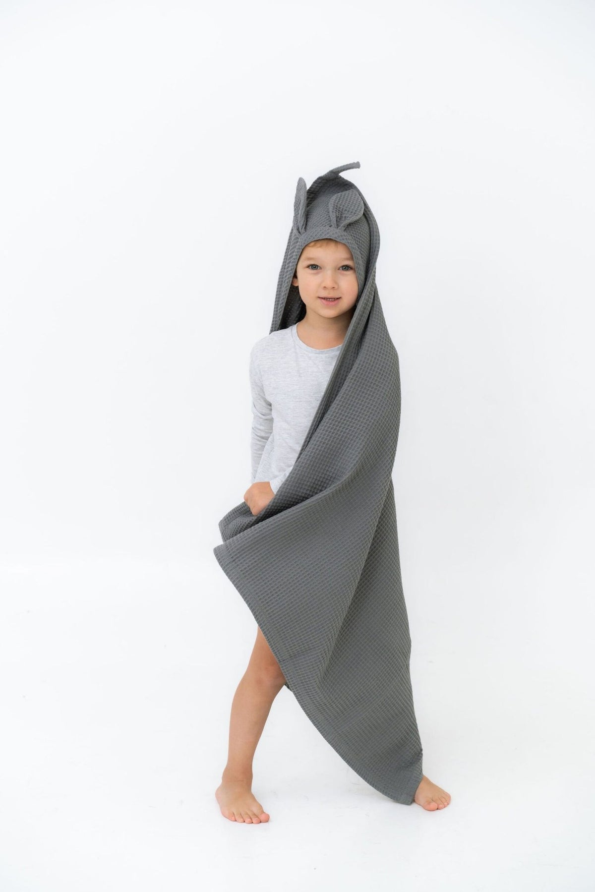 1. Child wearing gray waffle fabric towel with bunny ears hood standing on white background