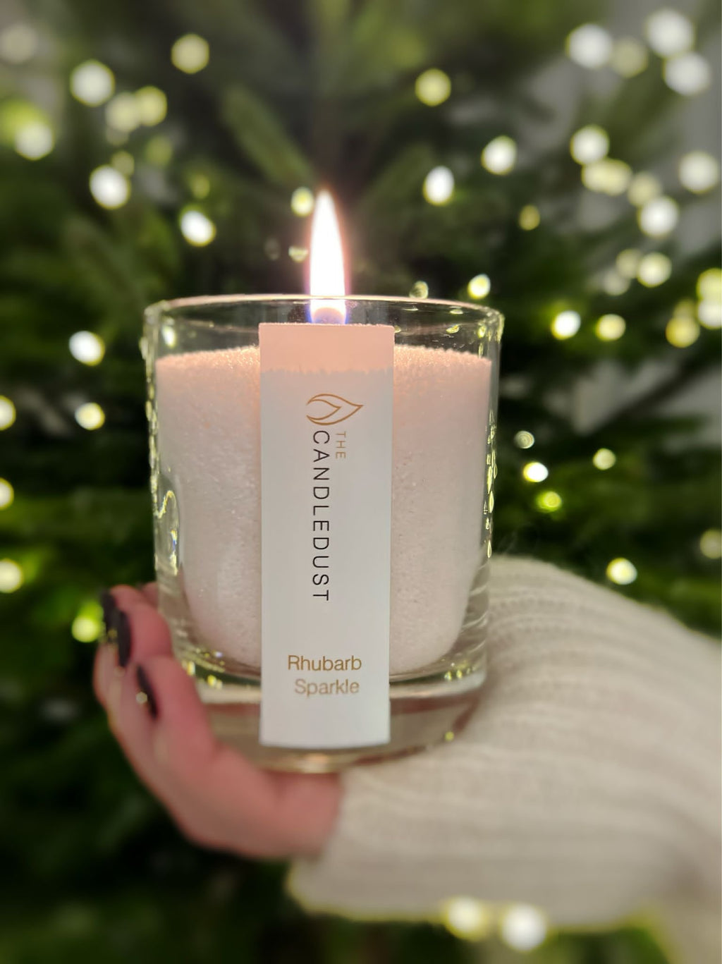 8. Candledust Rhubarb Sparkle powdered candle lit in front of a Christmas tree, creating festive atmosphere