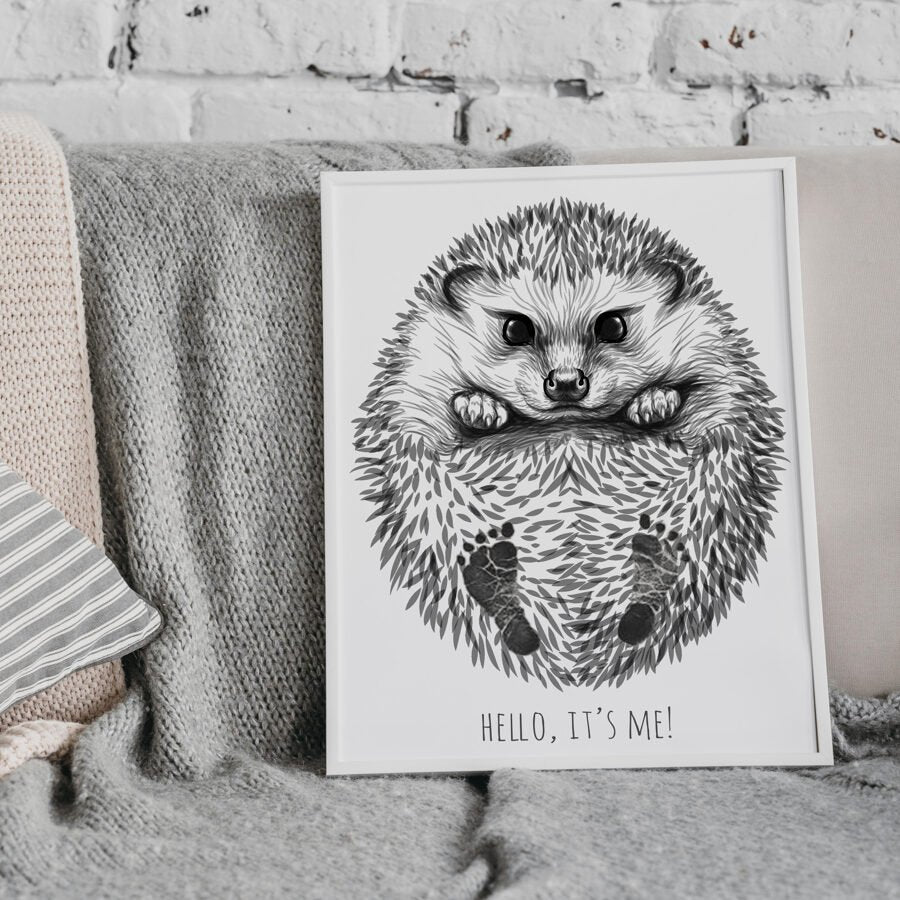 1. Personalized baby hedgehog footprint kit in white frame on a cozy couch, featuring hand-drawn hedgehog with baby footprints and text 'Hello, it's me!'