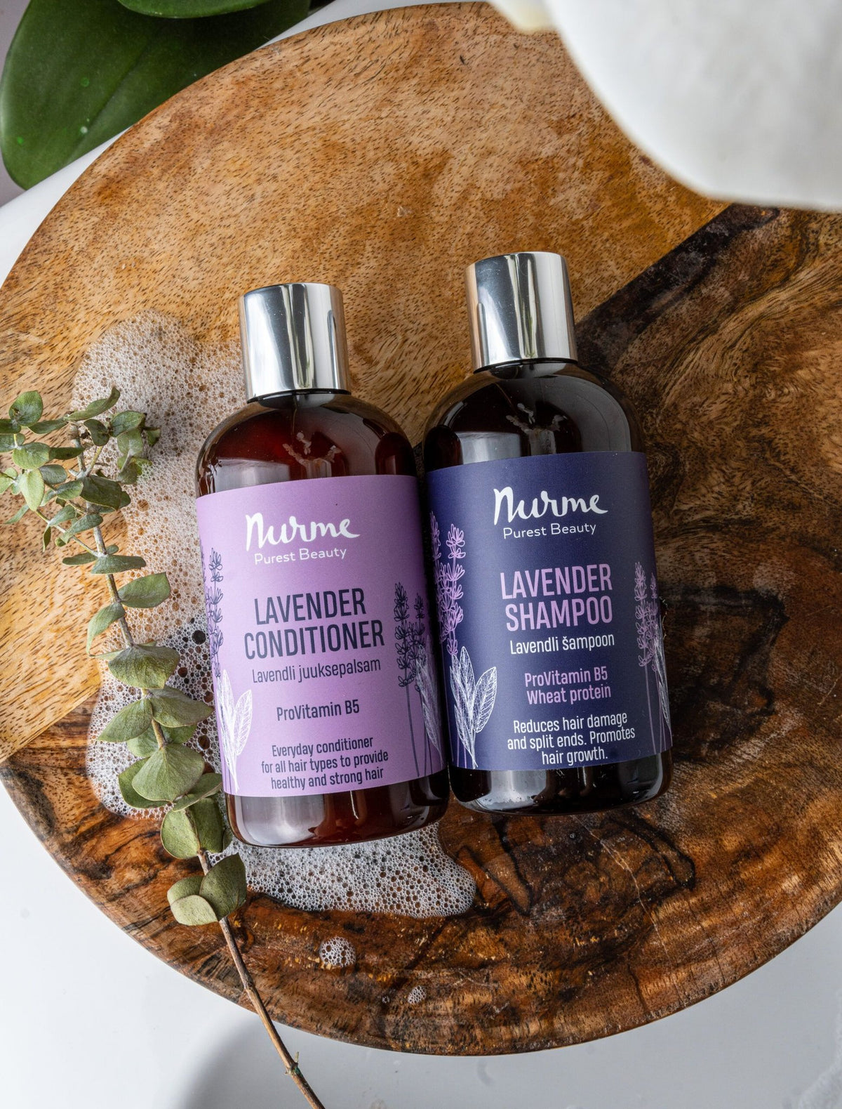 2. Nurme Lavender shampoo and conditioner bottles on wooden surface with eucalyptus, showcasing natural ingredients