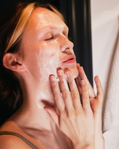 2. Woman applying Nurme Neroli Purifying Cream Cleanser to face, highlighting creamy texture