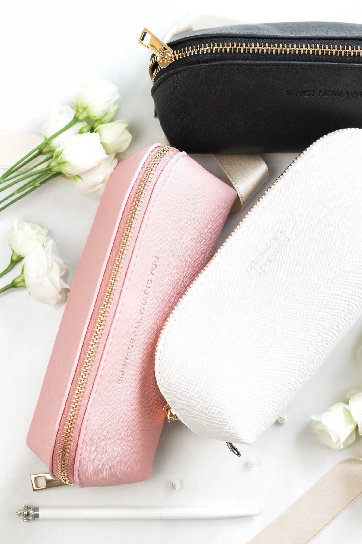 6. SEIK pencil cases in pink, white, and black stacked, showing gold zippers and text