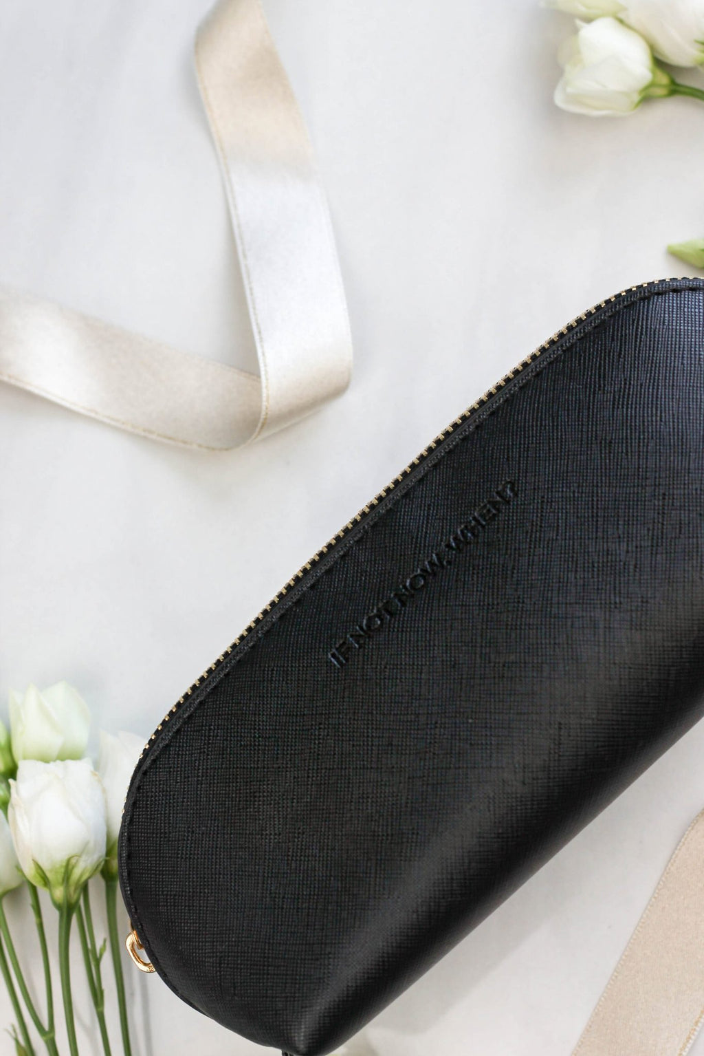 3. SEIK black pencil case with embossed 'IF NOT NOW, WHEN?' text, shown with flowers