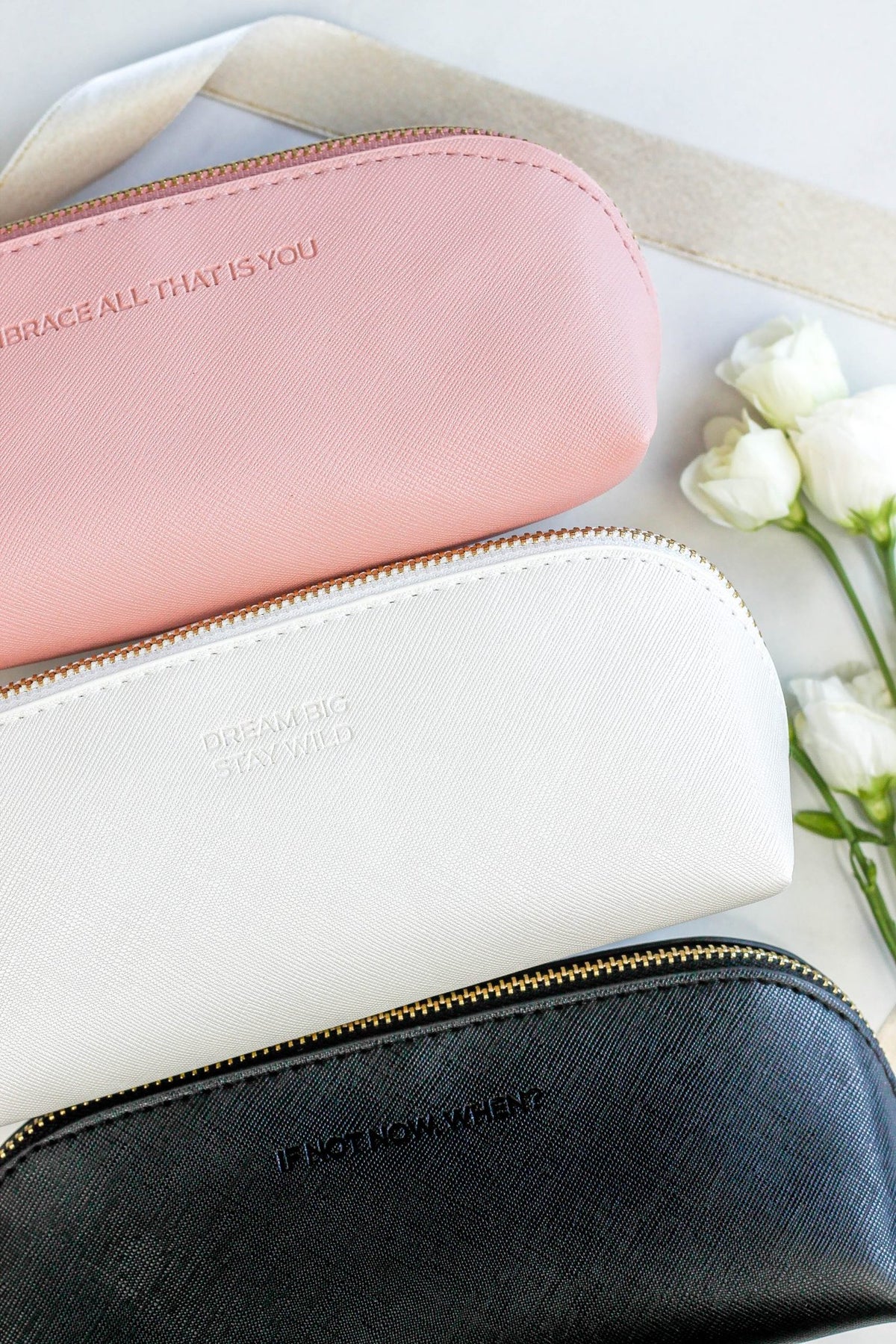 2. SEIK pencil cases in pink, white, and black, featuring embossed motivational phrases, displayed with flowers
