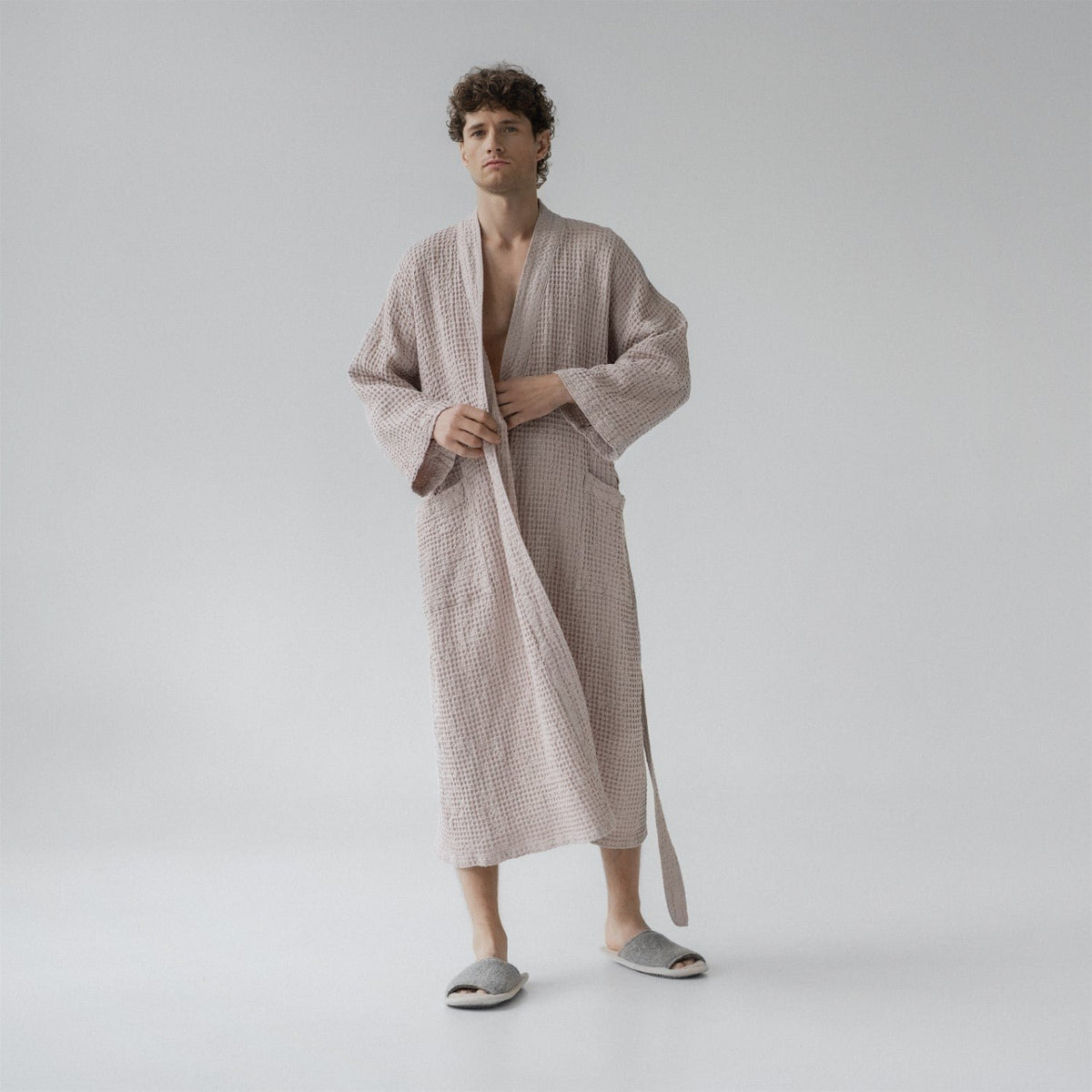 4. Man wearing powder-colored honeycomb waffle bathrobe with adjustable waist tie, standing in a studio