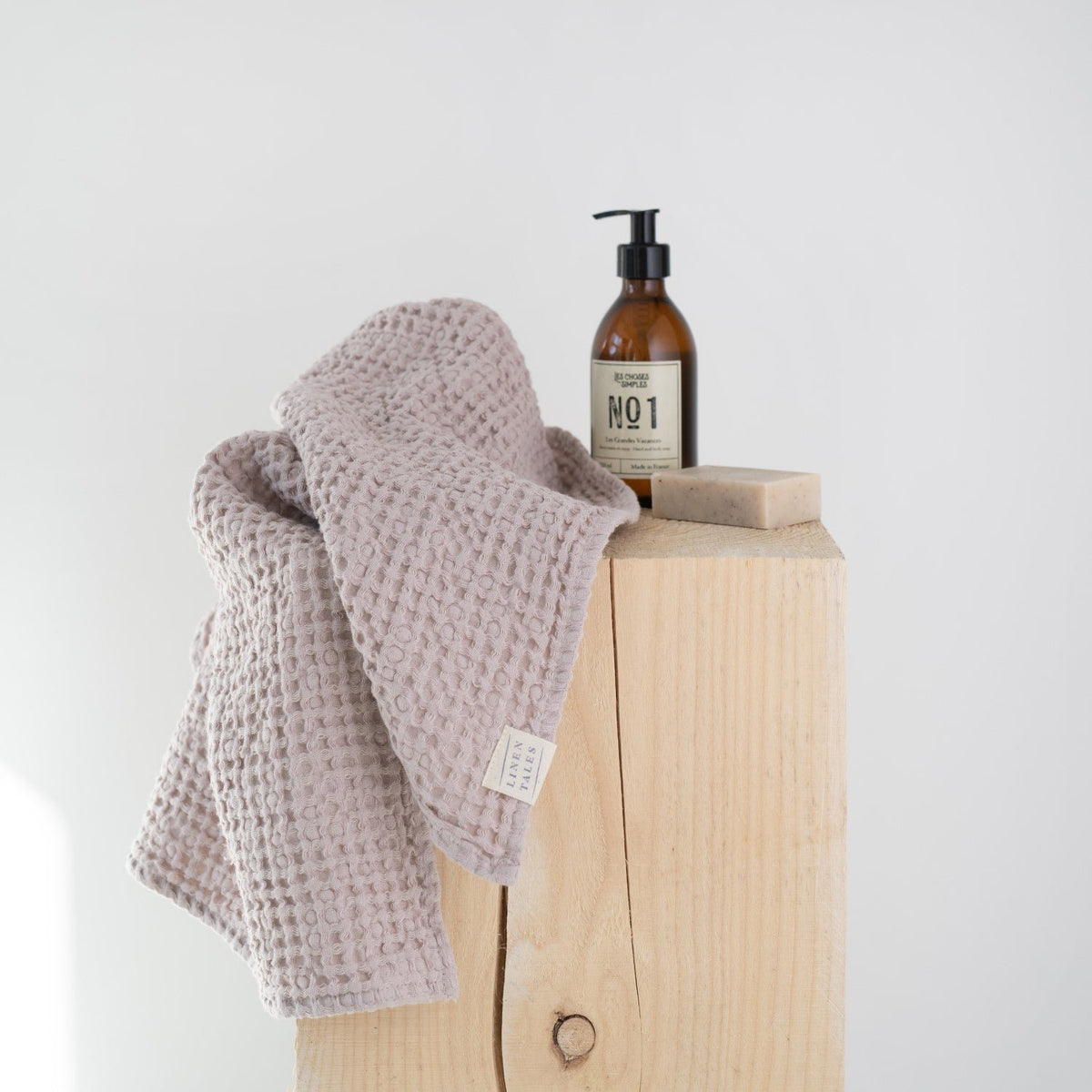 6. Powder-colored honeycomb waffle towel draped over wooden block with soap and lotion bottle