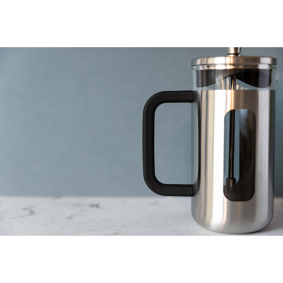 1. La Cafetière Pisa Coffee Maker in silver with black handle on marble surface against blue wall