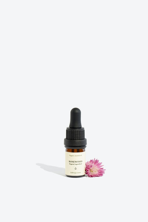 2. Smells Like Spells ROSEWOOD Essential Oil 5 ml bottle with pipette, styled with a pink flower, studio setting