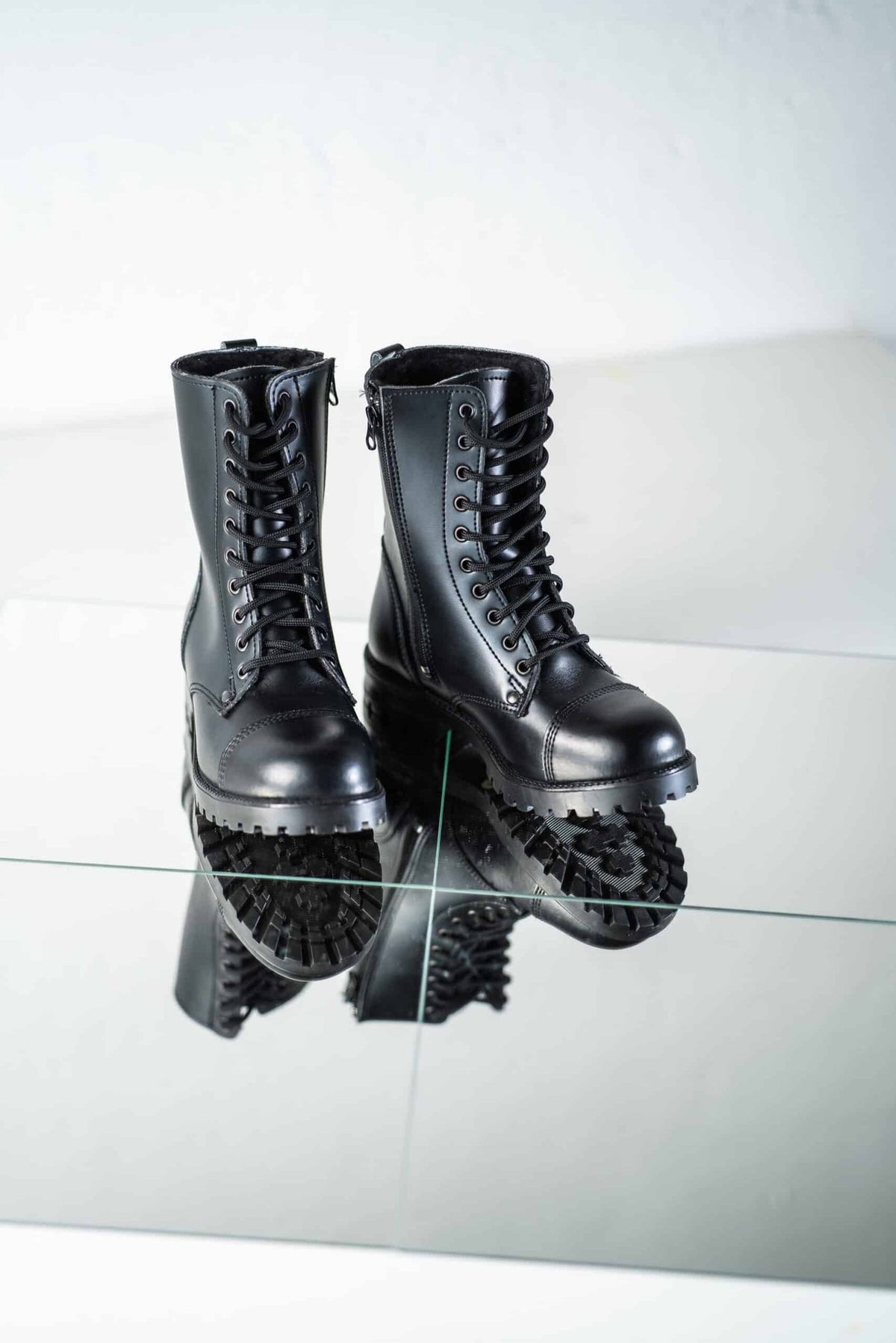 6. Pair of unisex black 511 Winter boots by Samelin on reflective surface, highlighting lace-up design