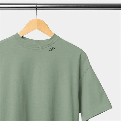 2. Green unisex organic cotton t-shirt with embroidered collar by Beebila, hanging on a wooden hanger