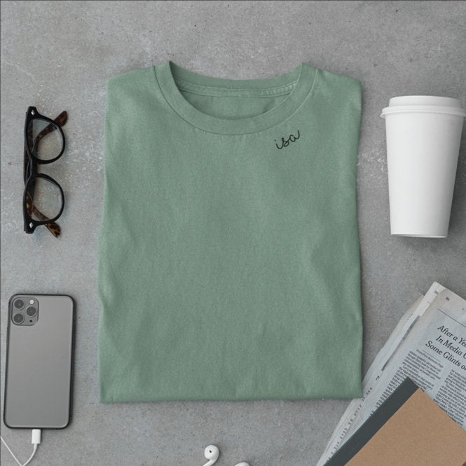 8. Flat lay of green organic cotton T-shirt by Beebila with embroidered collar, styled with accessories