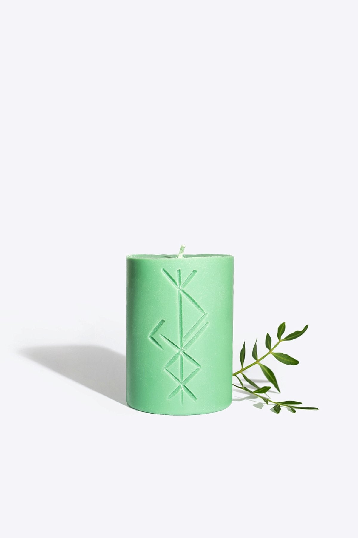 3. Smells Like Spells Rune candle FREYR in green with rune design, styled with greenery for a natural look