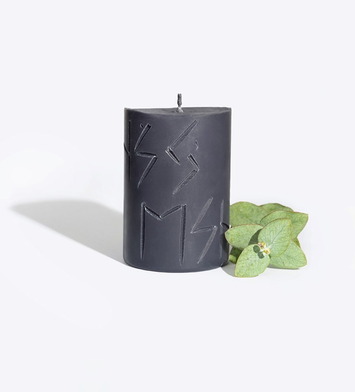 1. Handcrafted Rune Candle HAG by Smells Like Spells with engraved runes, shown with green leaves, made from pure soy wax