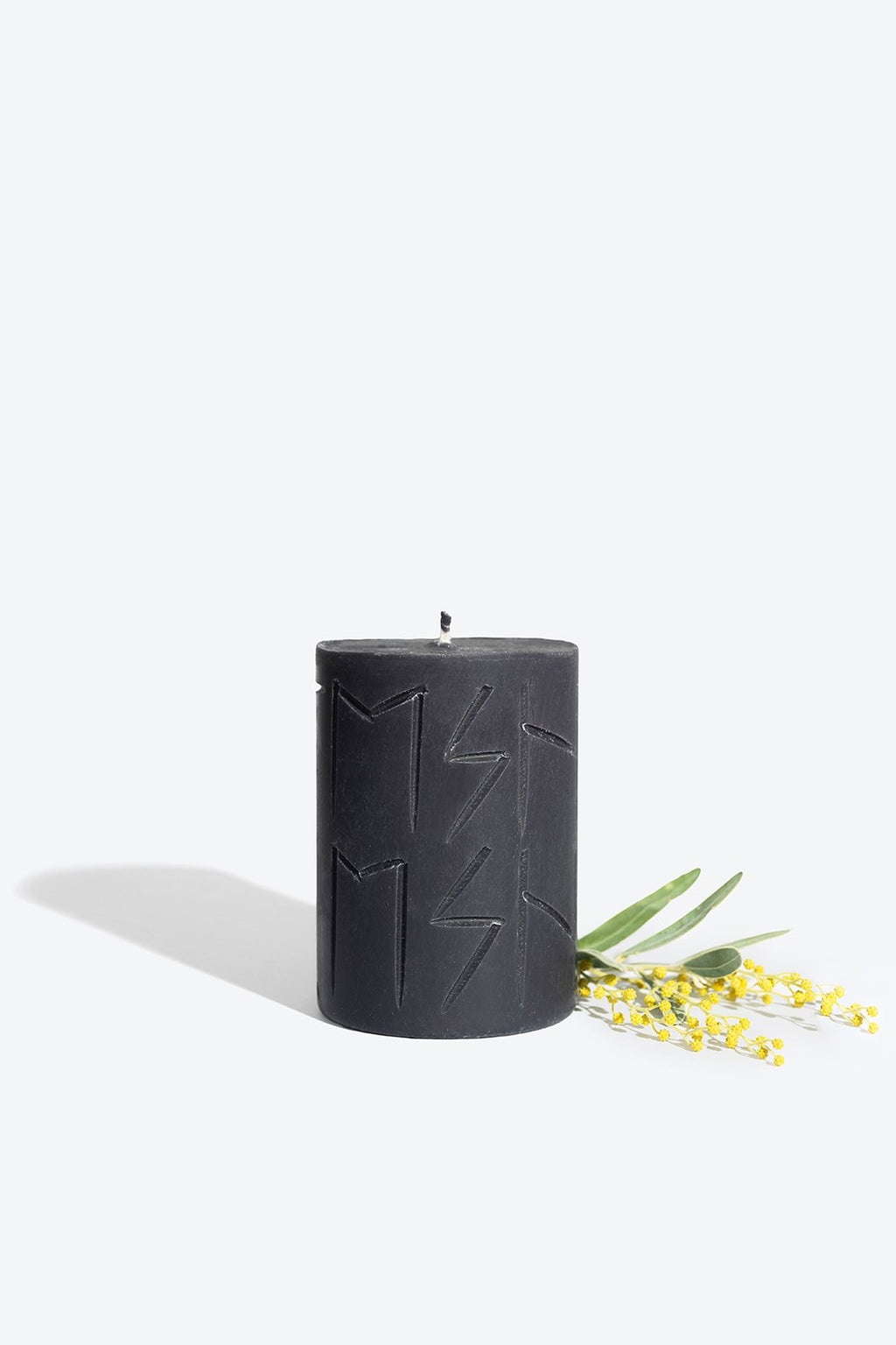 3. Smells Like Spells Rune Candle HEL in black with yellow floral accent, studio setting