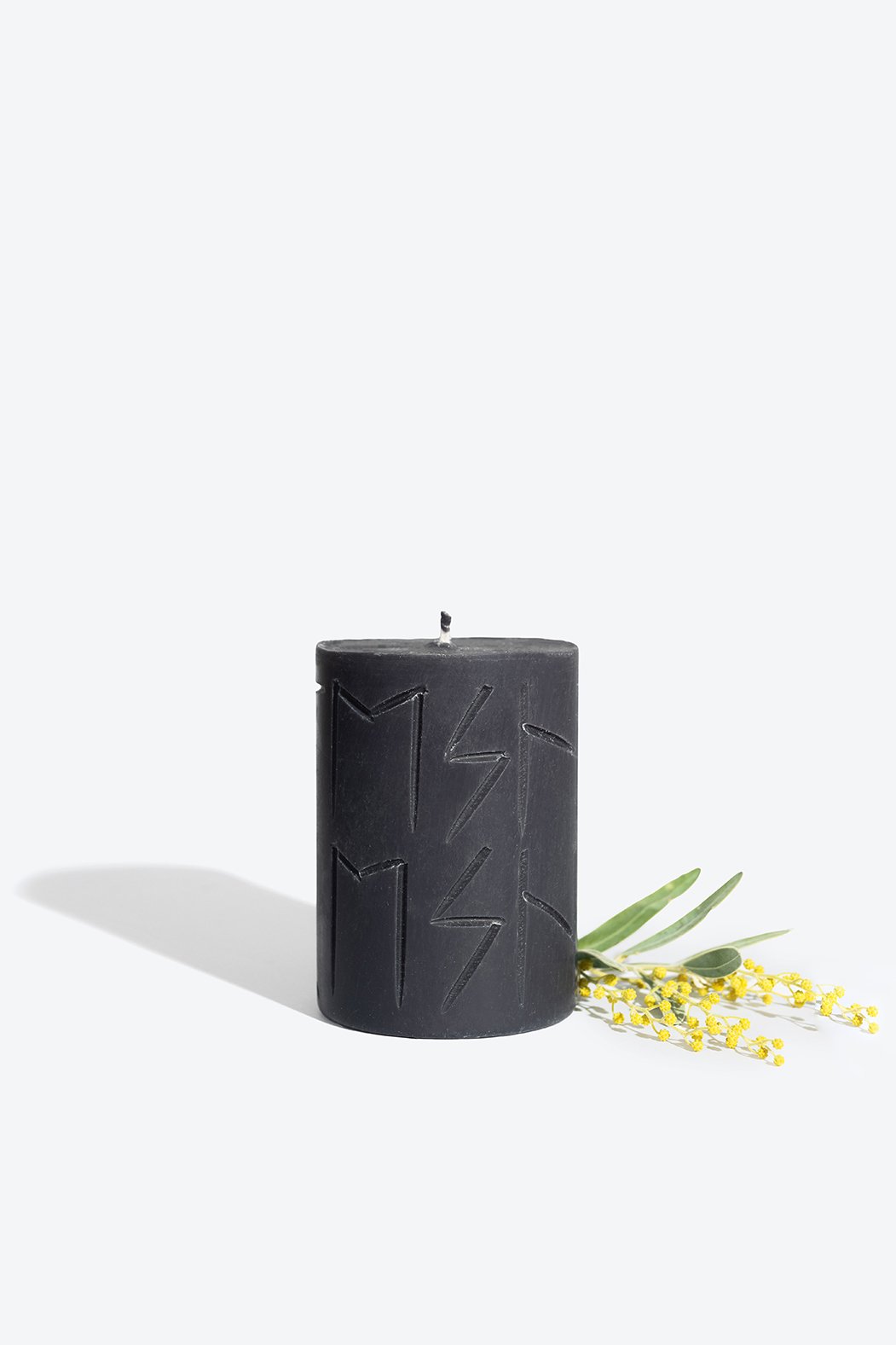 3. Smells Like Spells Rune Candle HEL in black with yellow floral accent, studio setting