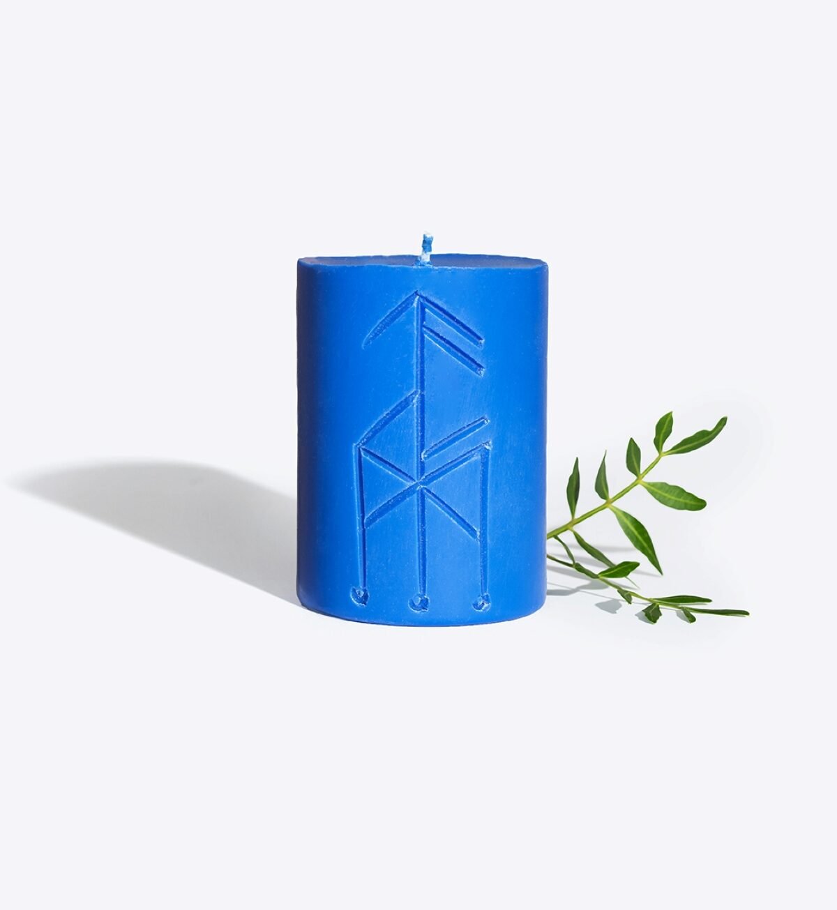 2. Smells Like Spells Rune candle THOR in blue, featuring rune design with green leaf accent, studio setting