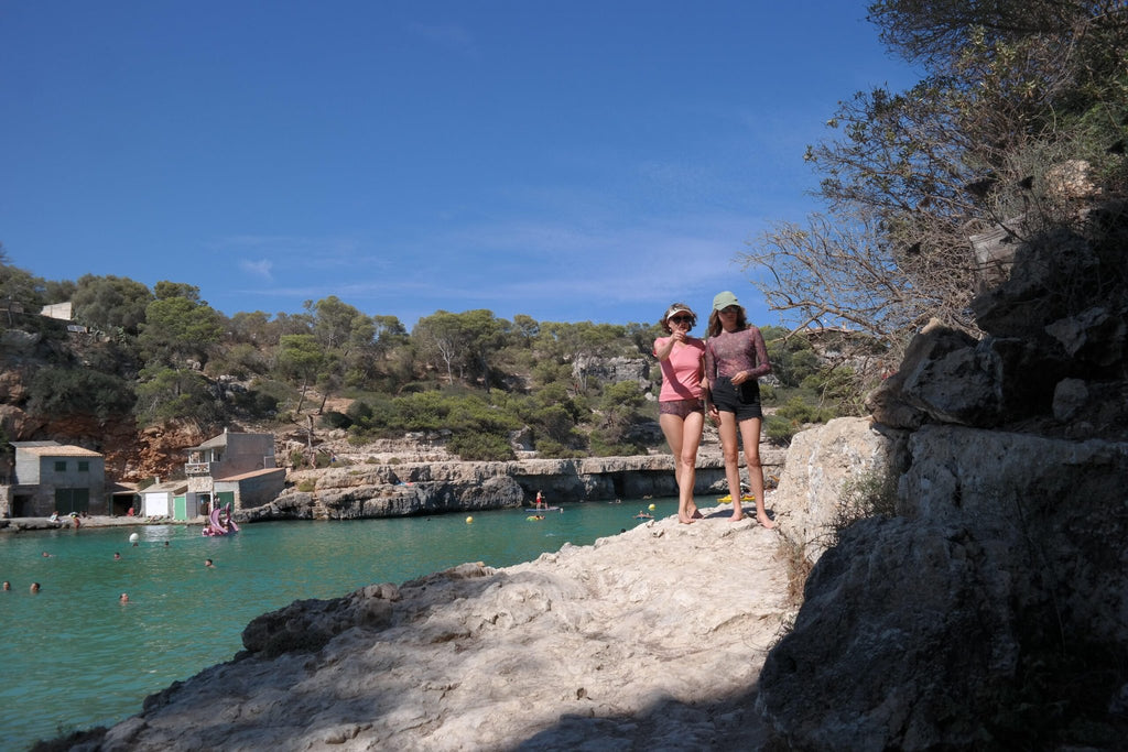1. Two women enjoying a sunny day by the beach, one wearing Smarttan's Tan-Through Mini Leggings in Blue Mandala
