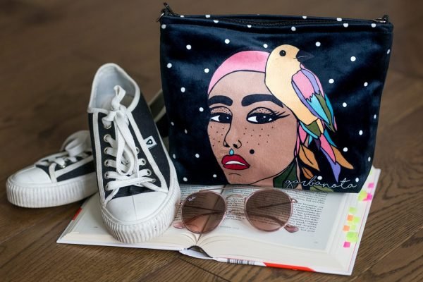 1. Garbanota black makeup bag with artistic print of a woman and bird, shown in studio setting