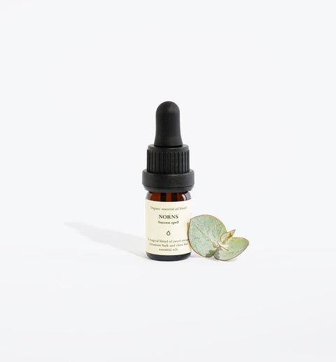 1. Smells Like Spells Essential Oil Blend NORNS in 5 ml glass bottle with pipette, shown with eucalyptus leaf in studio setting