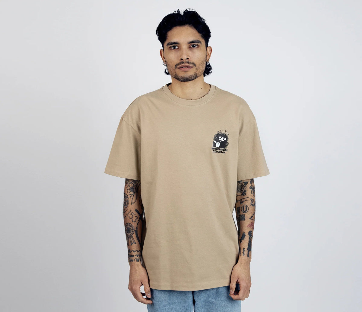 2. Men's unisex Stinky Plotting T-Shirt by Moomin, front view with small logo, styled with tattoos in studio